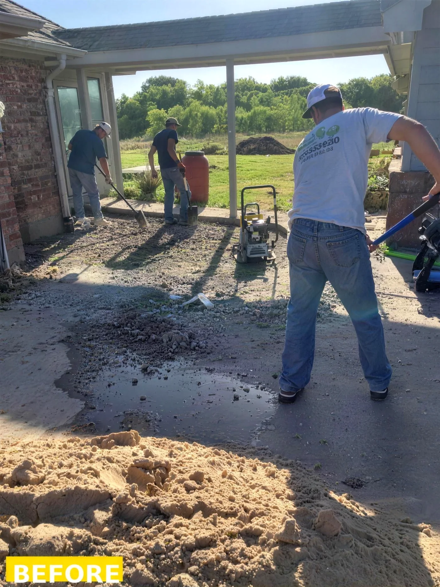 Same patio area before hardscaping - rough gravel base and crew prepping the site