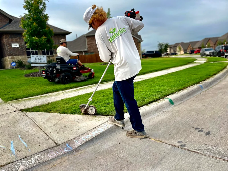 Mahalic and Sons crew member edging a driveway for a crisp, clean lawn line
