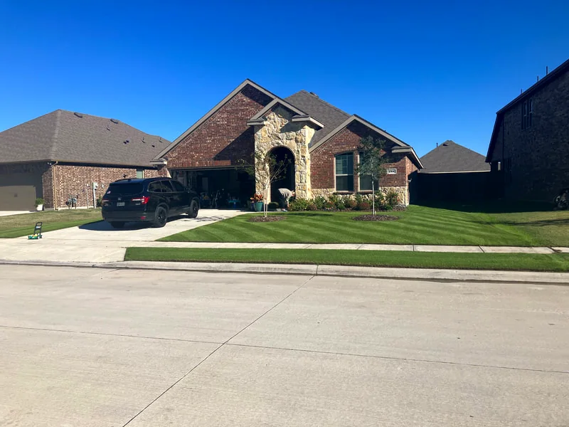 Trimmed lawn in front of a brick home